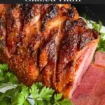 Brown sugar glazed ham on a platter garnished with fresh parsley.