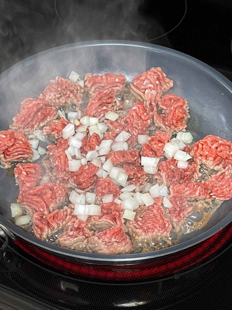 Ground beef with onions browning in a skillet.