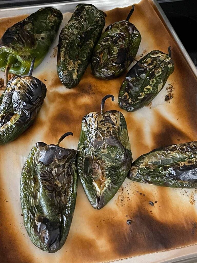 Roasted poblano peppers on a baking sheet.