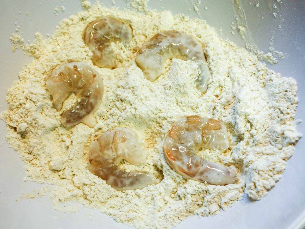 Raw shrimp in the seasoned flour mixture.