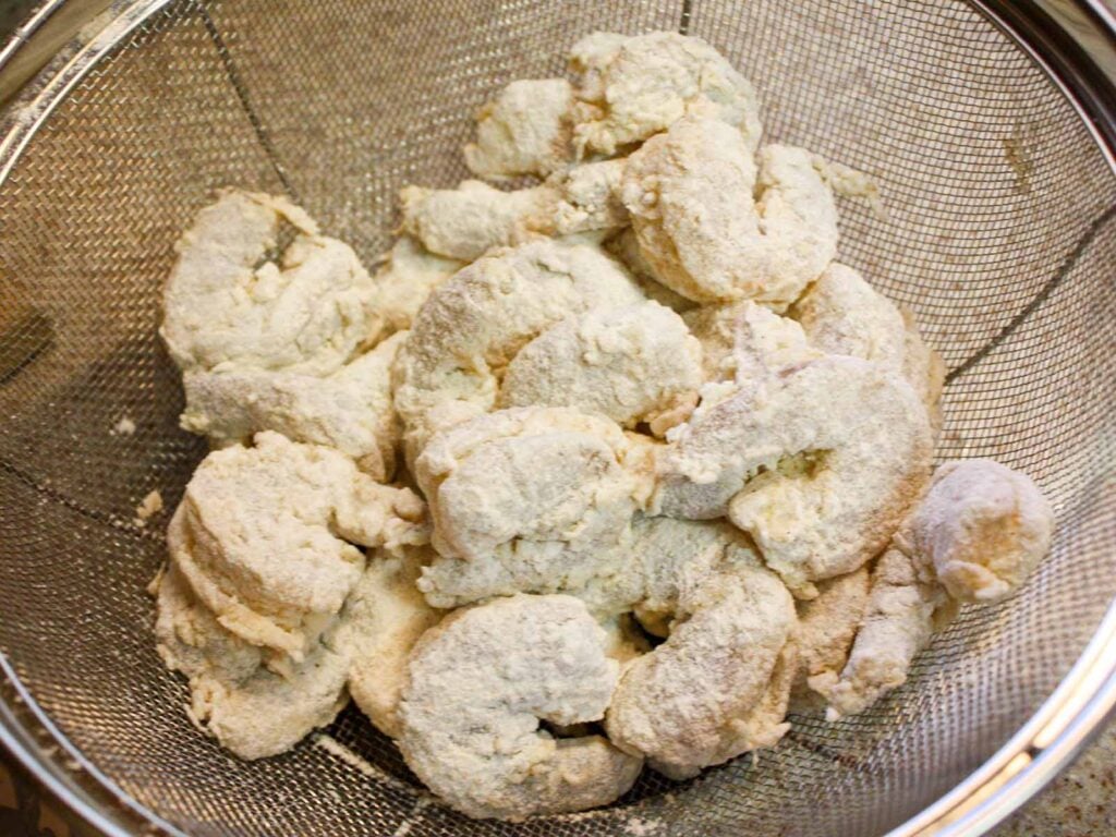 Battered shrimp in a strainer.