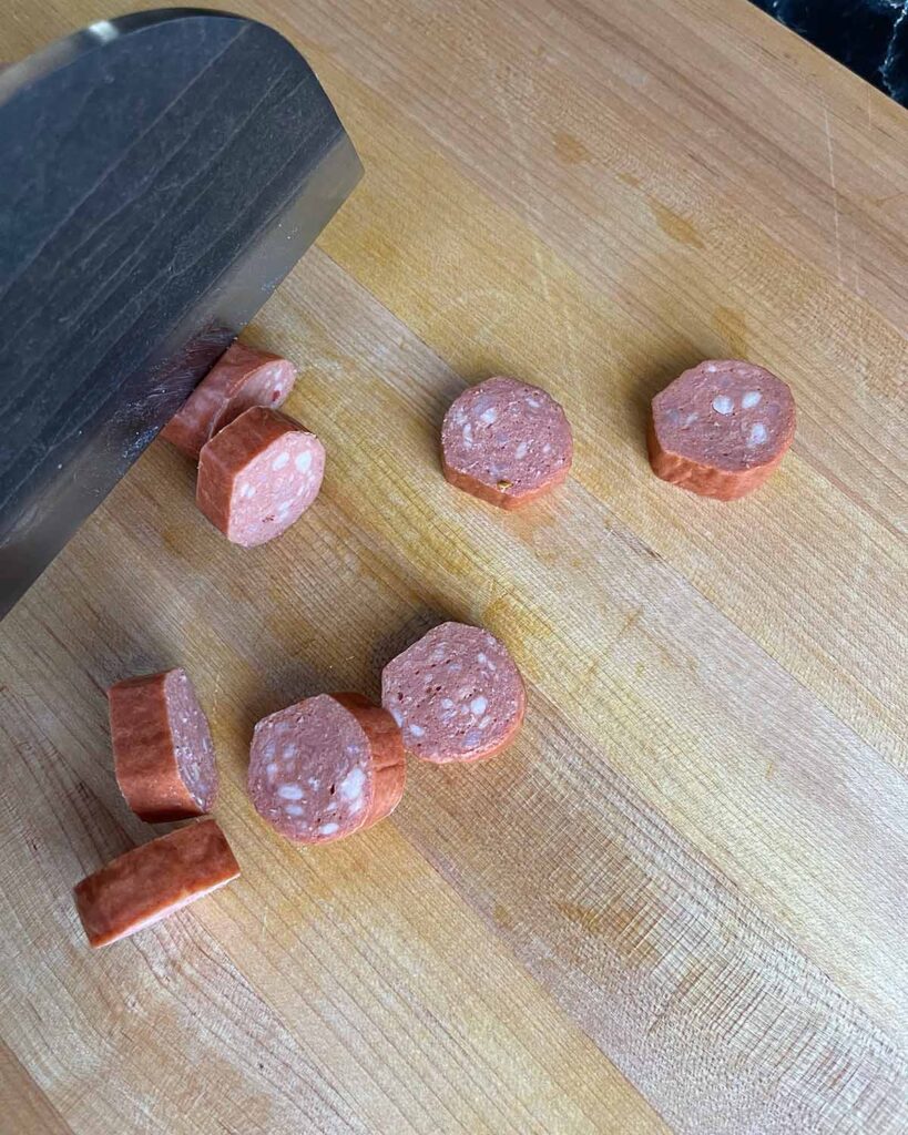 Cutting smoked sausage on a cutting board.