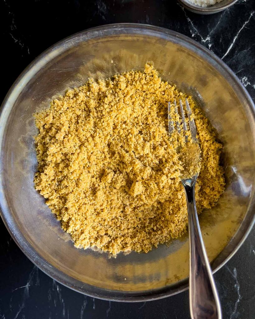 Crust ingredients mixed together in a metal bowl with a fork.