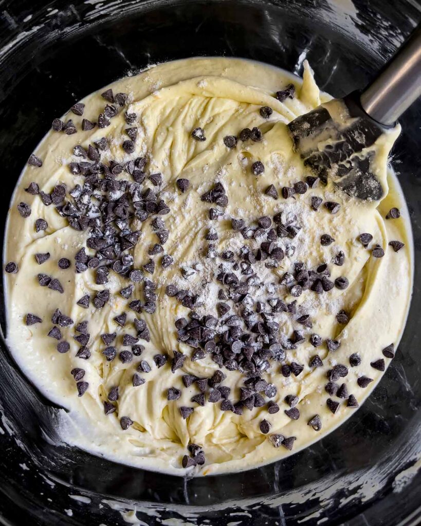 Mini chocolate chips being folded into the cannoli cheesecake batter.