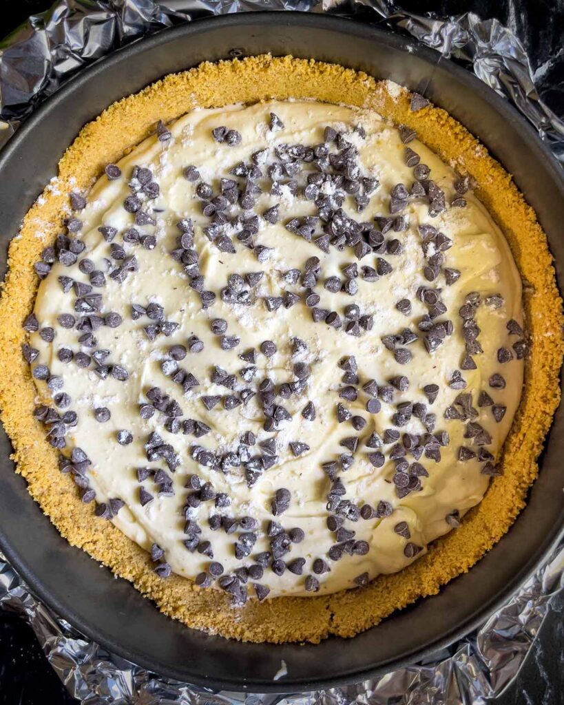 Cannoli cheesecake batter layered with chocolate chips in the springform pan.
