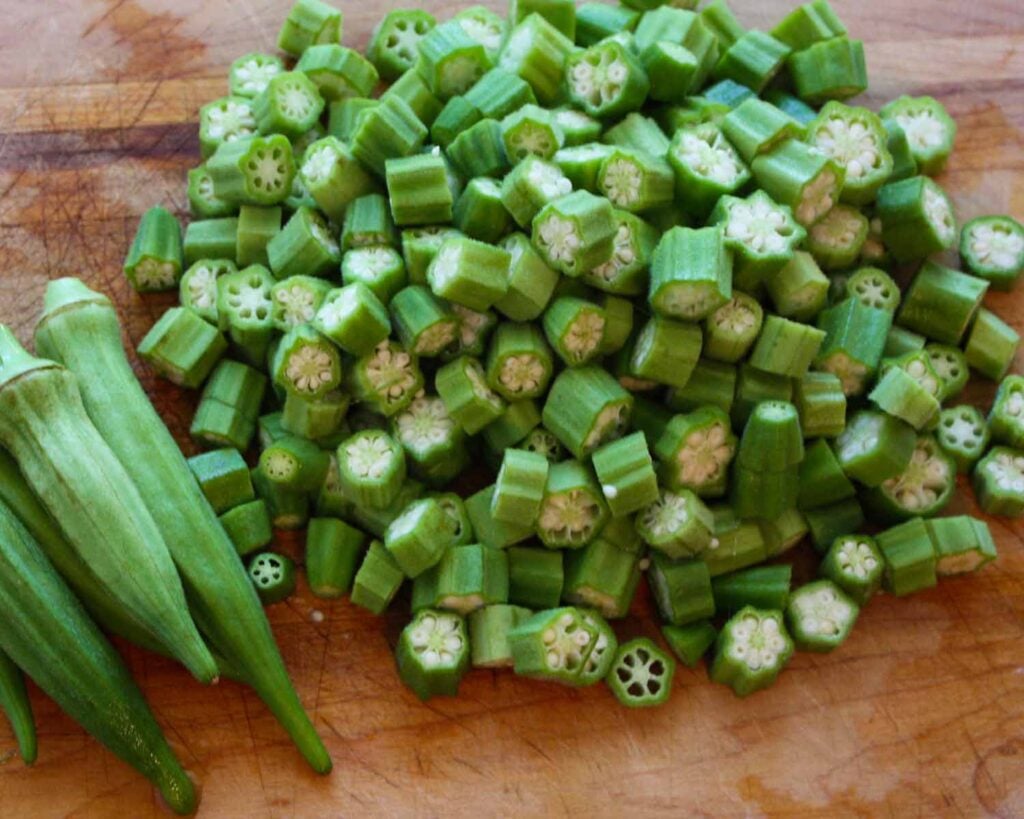 Okra cut into small pieces on a cutting board.