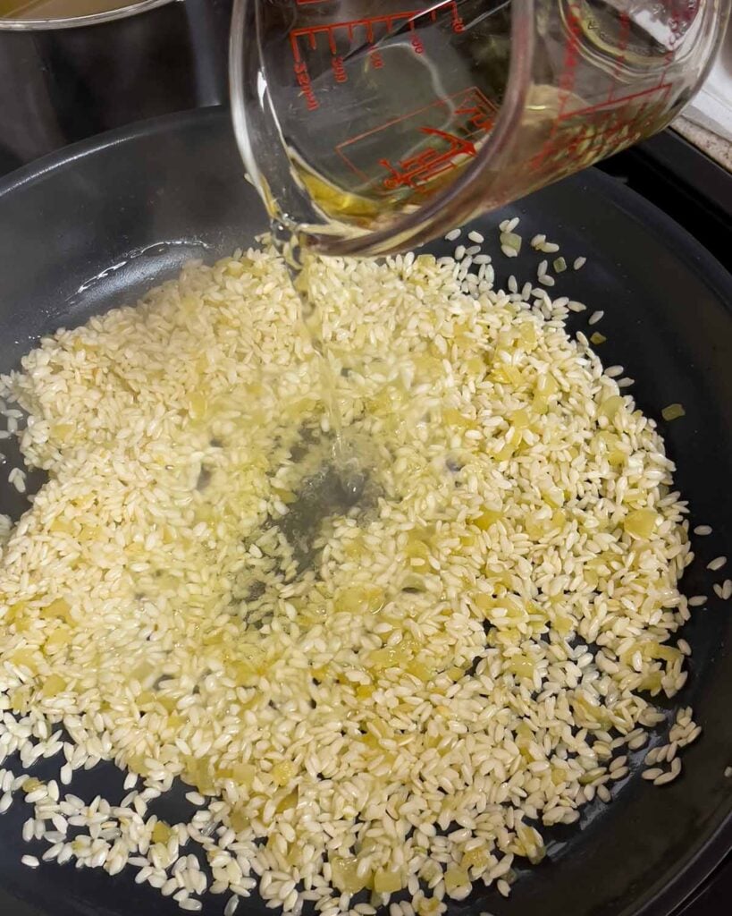 Adding white wine to risotto.