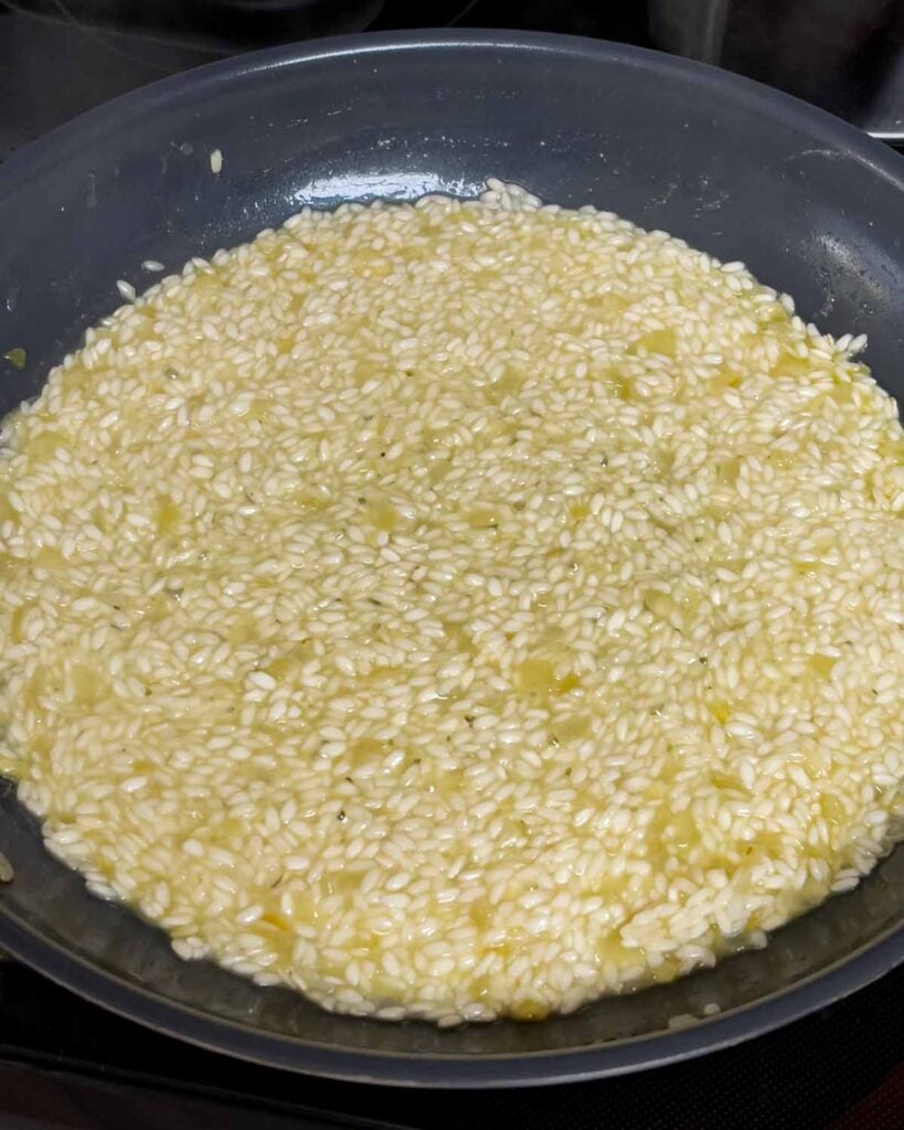 A ladle of stock almost absorbed into risotto.