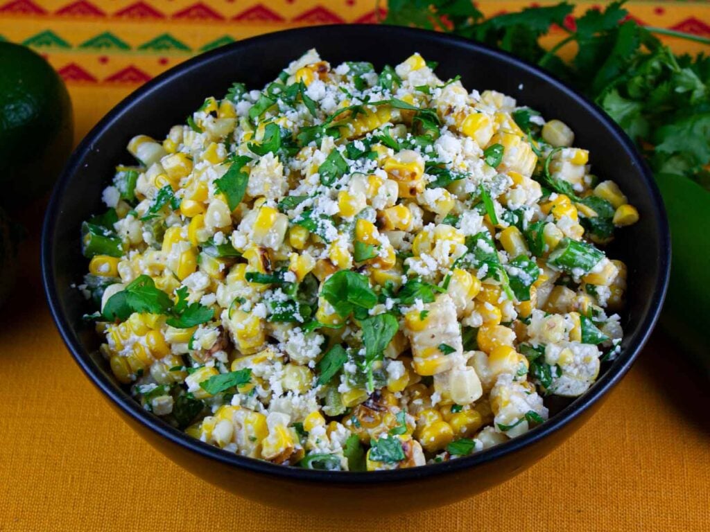 Grilled Mexican street corn salad in a dark bowl.