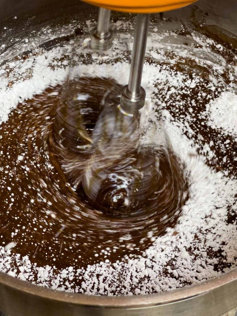 Powdered sugar being beaten into the chocolate frosting for the Mississippi Mud Cake.