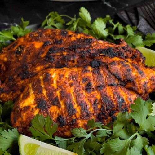 Pechuga asada on a bed of cilantro with limes.