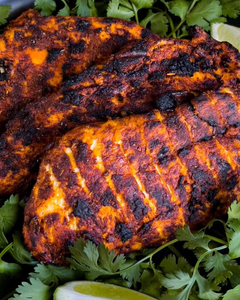 Mexican grilled chicken breasts on a bed of cilantro.