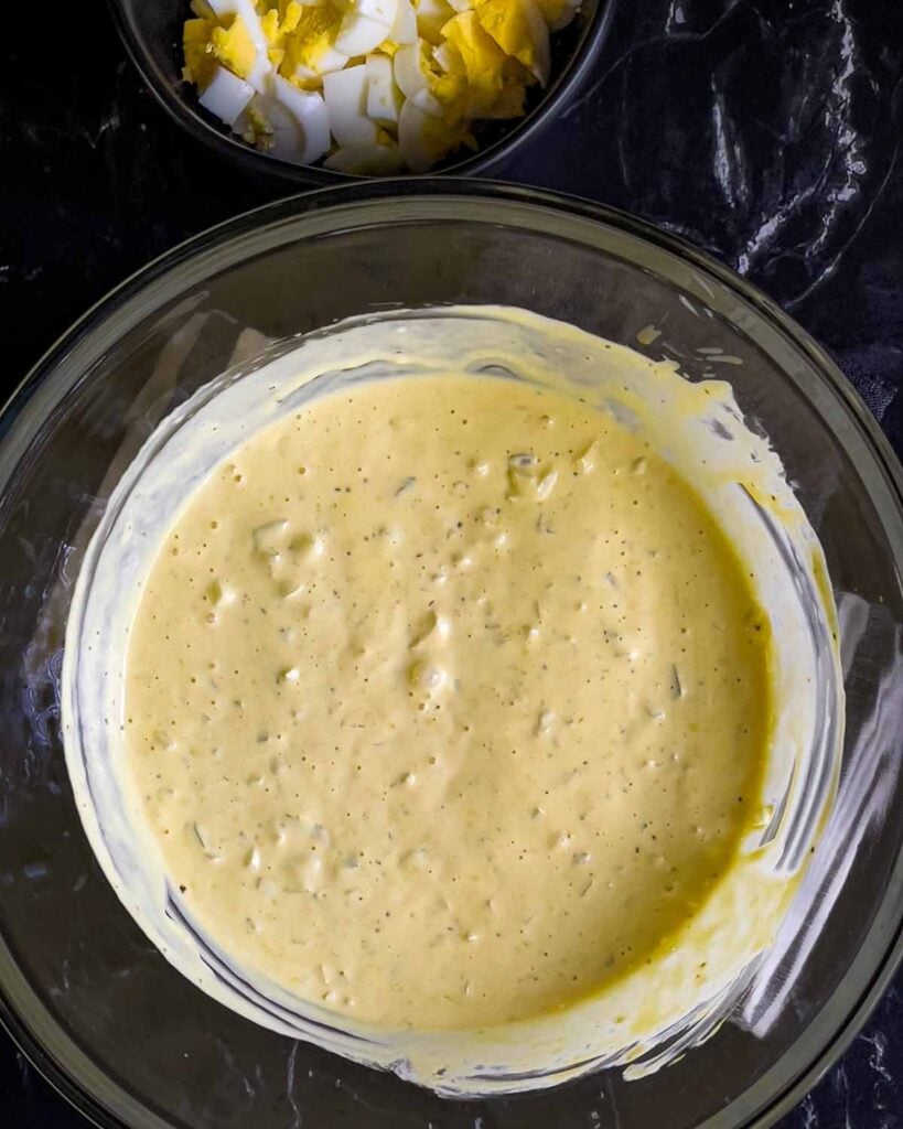 Southern potato salad dressing combined in a large glass mixing bowl