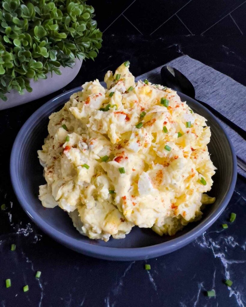 Southern potato salad in a bowl garnished with chives and paprika.