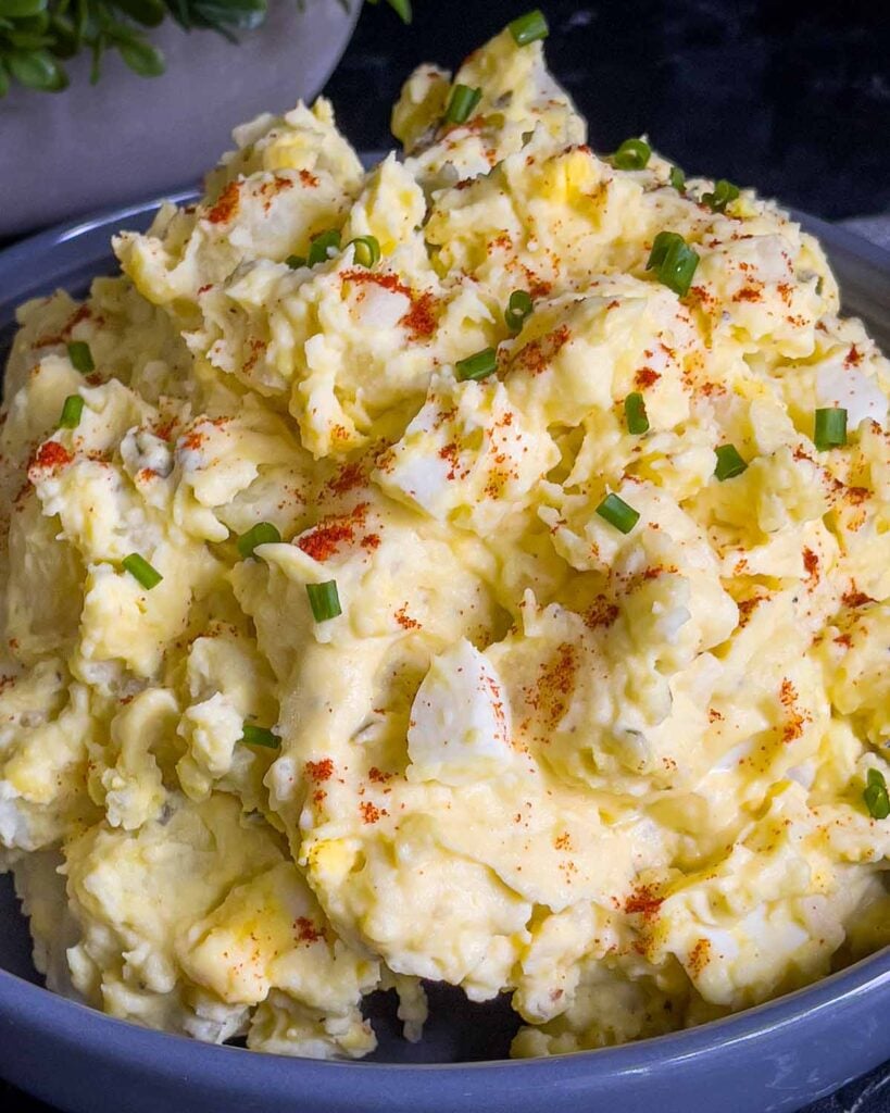 Southern potato salad in a bowl garnished with chives and paprika.