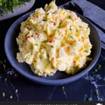 Southern potato salad in a bowl garnished with chives and paprika.