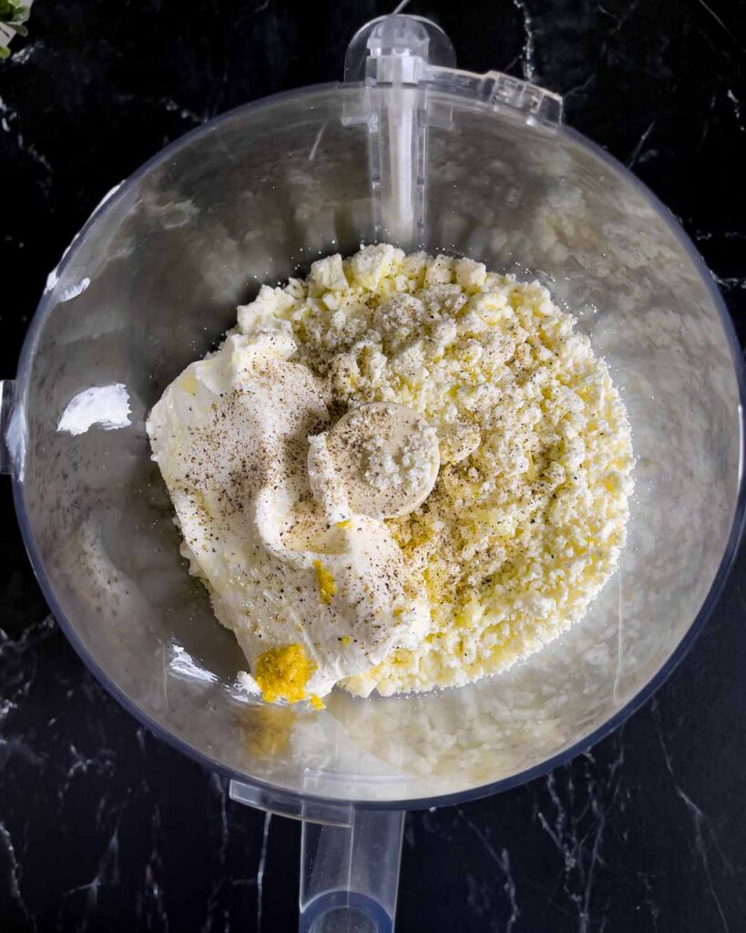 Whipped feta ingredients in the bowl of a food processor.