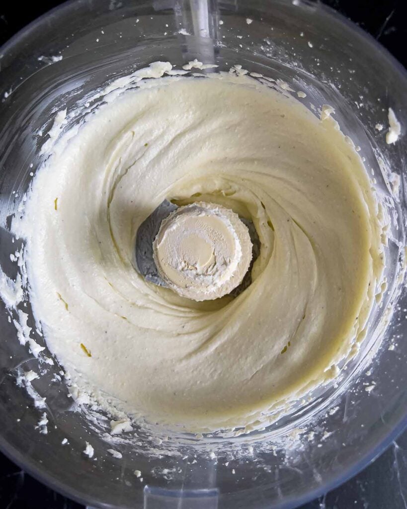 Smooth whipped feta in the bowl of a food processor.