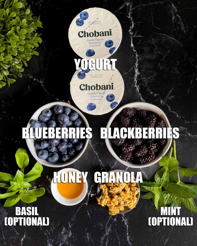 Ingredients for a berry yogurt parfait on a dark surface.