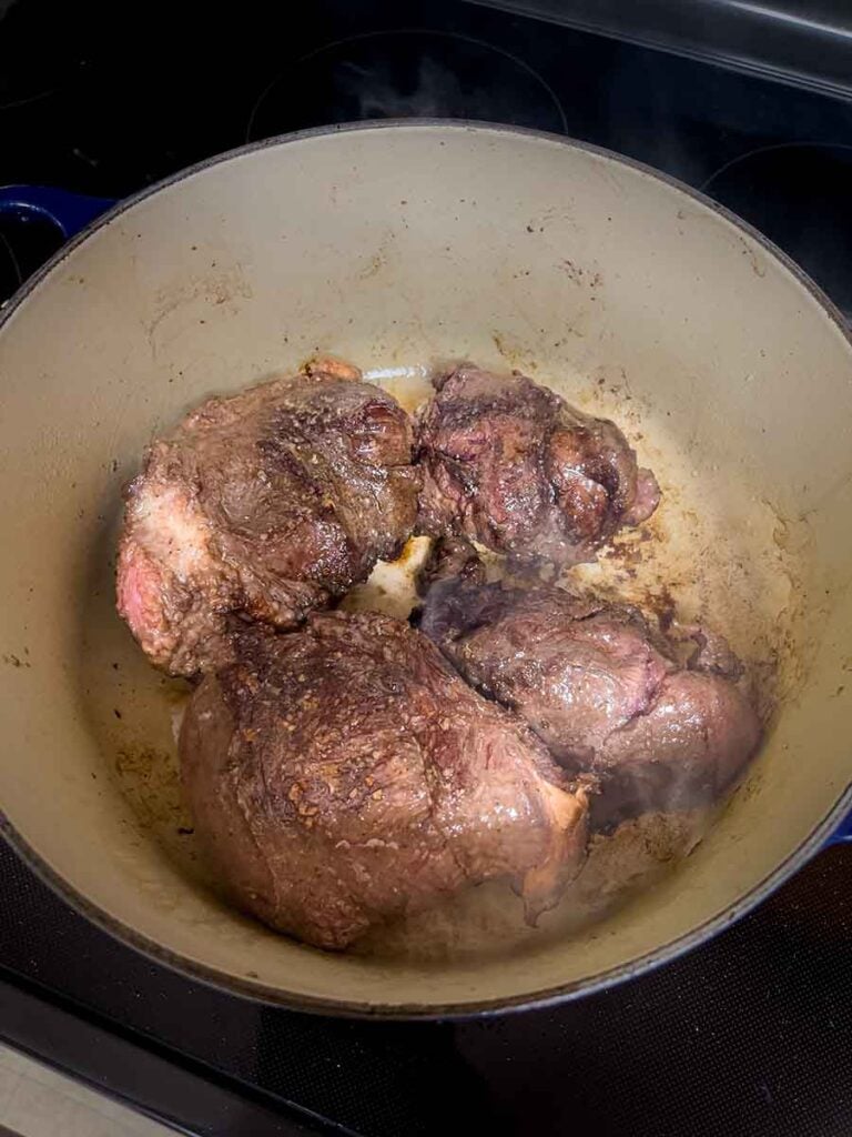 Beef cheek being browned in a dutch oven.