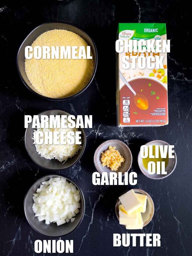 Ingredients for a basic polenta laid out on a black marble countertop.