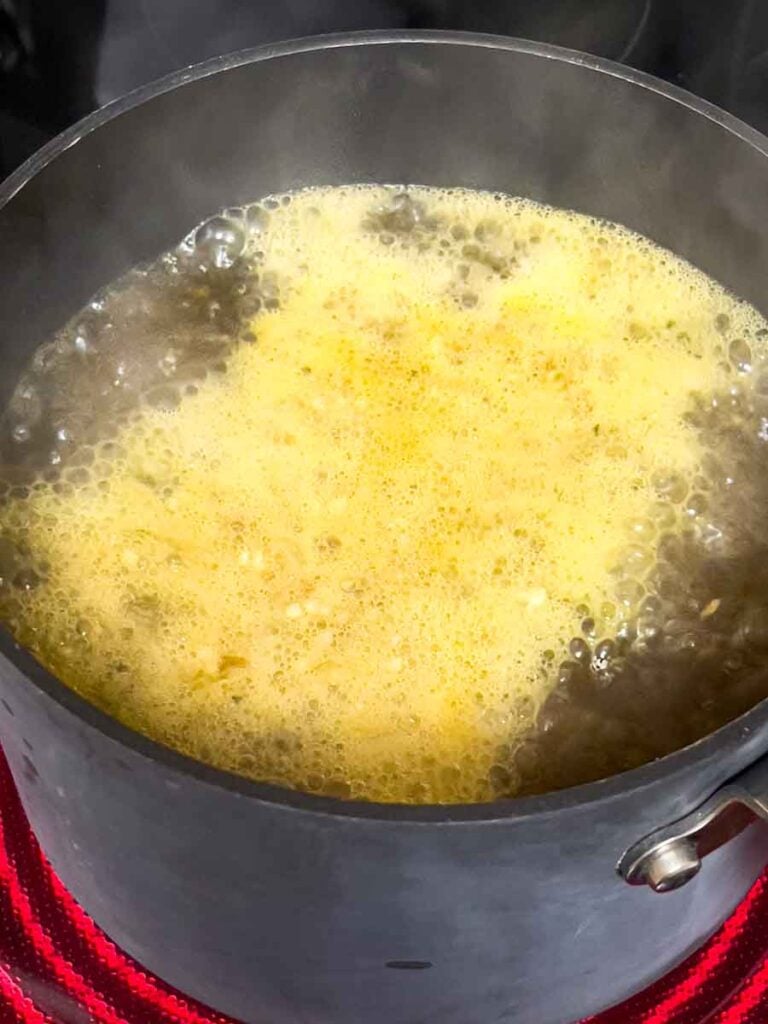 Chicken stock boiling on the stovetop.