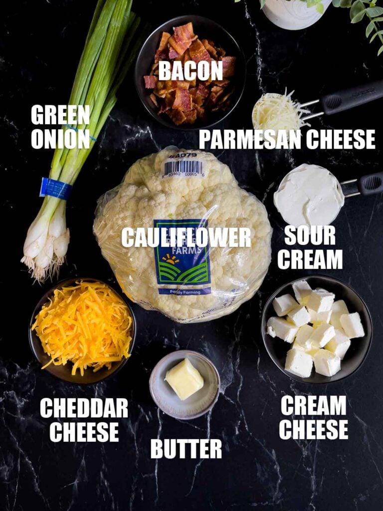 Ingredients for Loaded Cauliflower Mash Casserole on a dark surface.