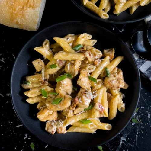 Cajun chicken pasta served in a dark bowl on a dark surface.