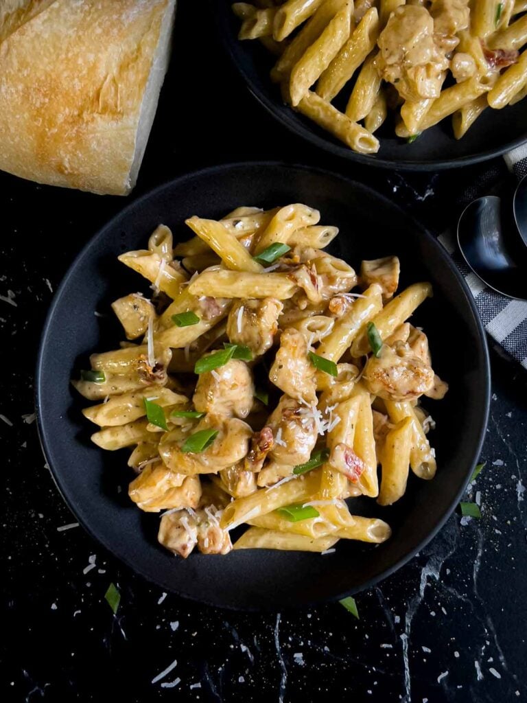 Cajun chicken pasta served in a dark bowl on a dark surface.