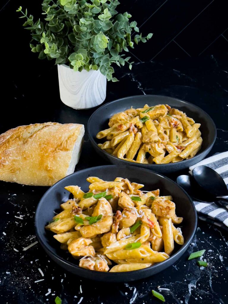 Cajun chicken pasta served in a dark bowl on a dark surface.