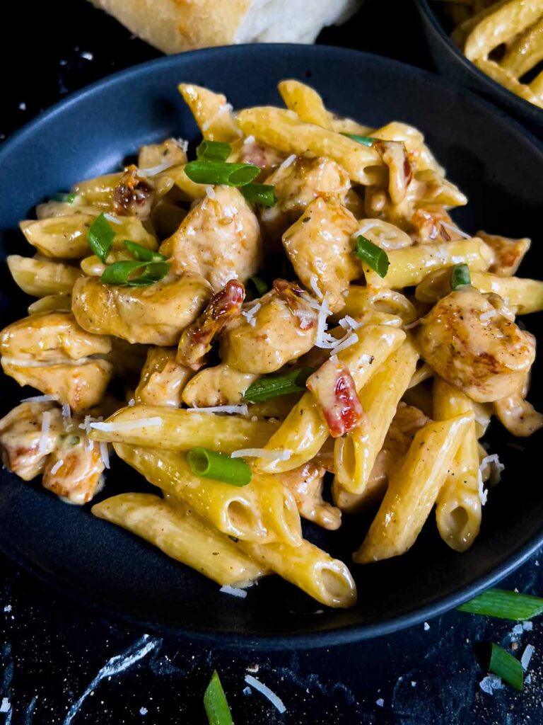 Cajun chicken pasta served in a dark bowl on a dark surface.