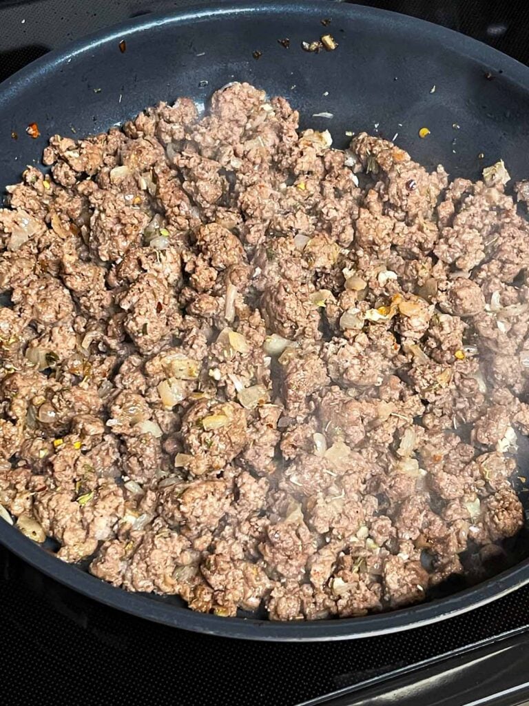 Ground beef browning in a large skillet.