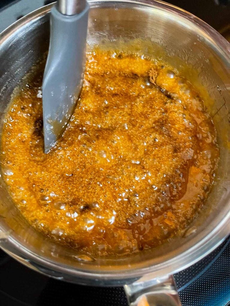 Butter and sugar mixture for oyster cracker churro snack mix boiling in a saucepan.