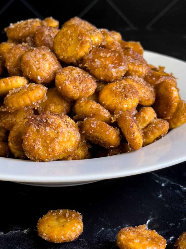 Oyster cracker churro snack mix in a light bowl on a dark surface.