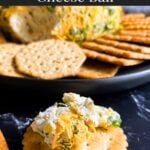 Dill pickle cheese ball scooped on a cracker on a dark surface.