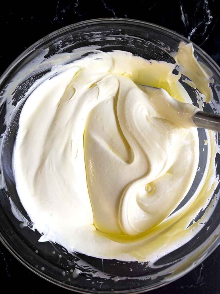 The pudding filling for the lemon icebox cake in a glass mixing bowl on a dark surface.