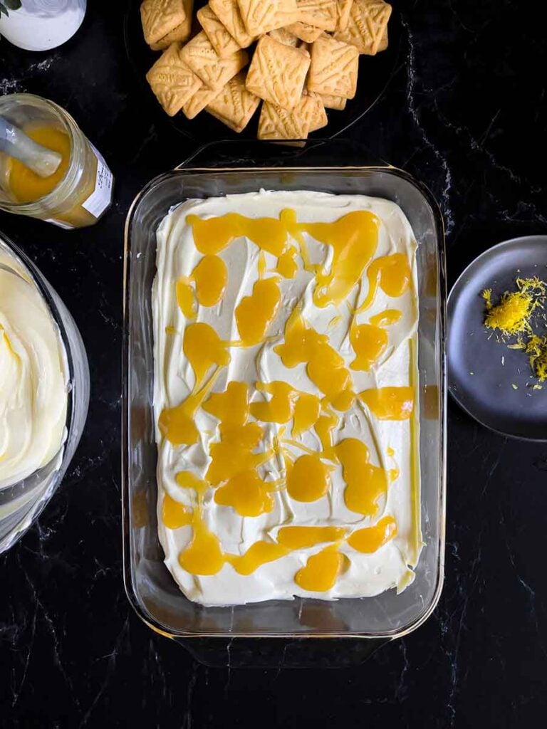 First layer of the lemon icebox cake completed in a glass baking dish on a dark surface.