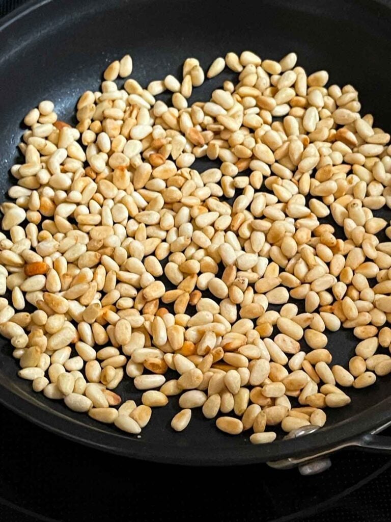 Toasted pine nuts in a dry skillet for the spinach and feta orzo salad.
