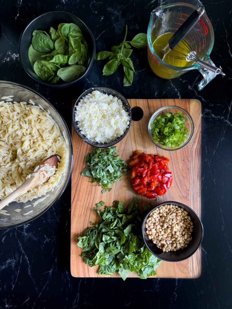 Add-ins for the spinach and feta orzo salad on a dark surface.