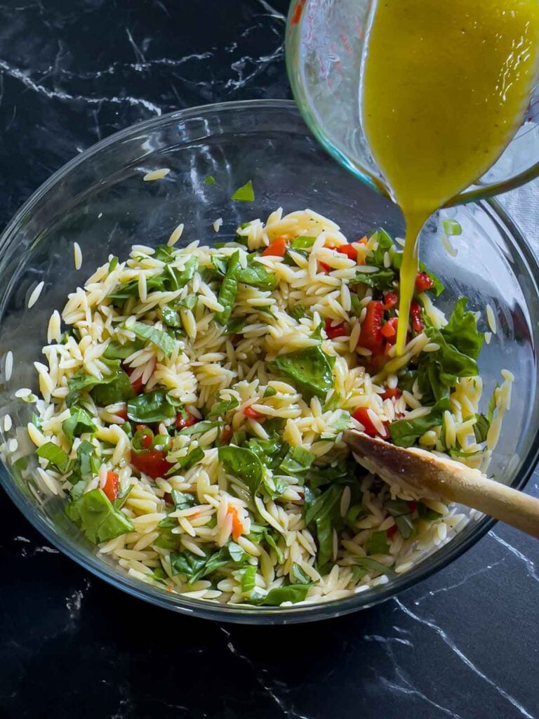 Dressing being added to the spinach and feta orzo salad.