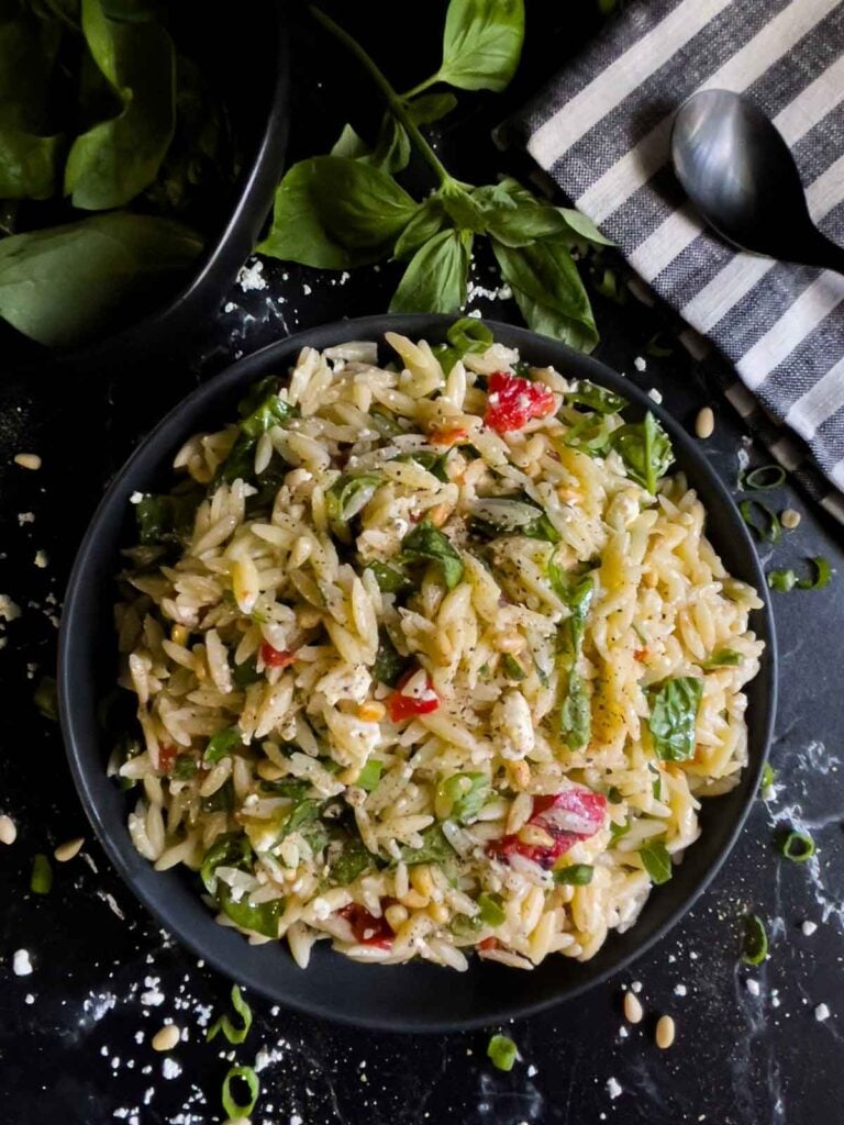 Spinach and Feta Orzo Salad in a dark bowl on a dark surface.