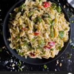 Spinach and Feta Orzo Salad in a dark bowl on a dark surface.