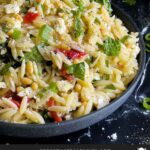 Spinach and Feta Orzo Salad in a dark bowl on a dark surface.