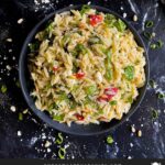 Spinach and Feta Orzo Salad in a dark bowl on a dark surface.