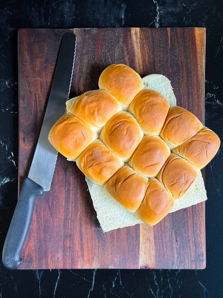 Slider rolls sliced in half on a dark cutting board.