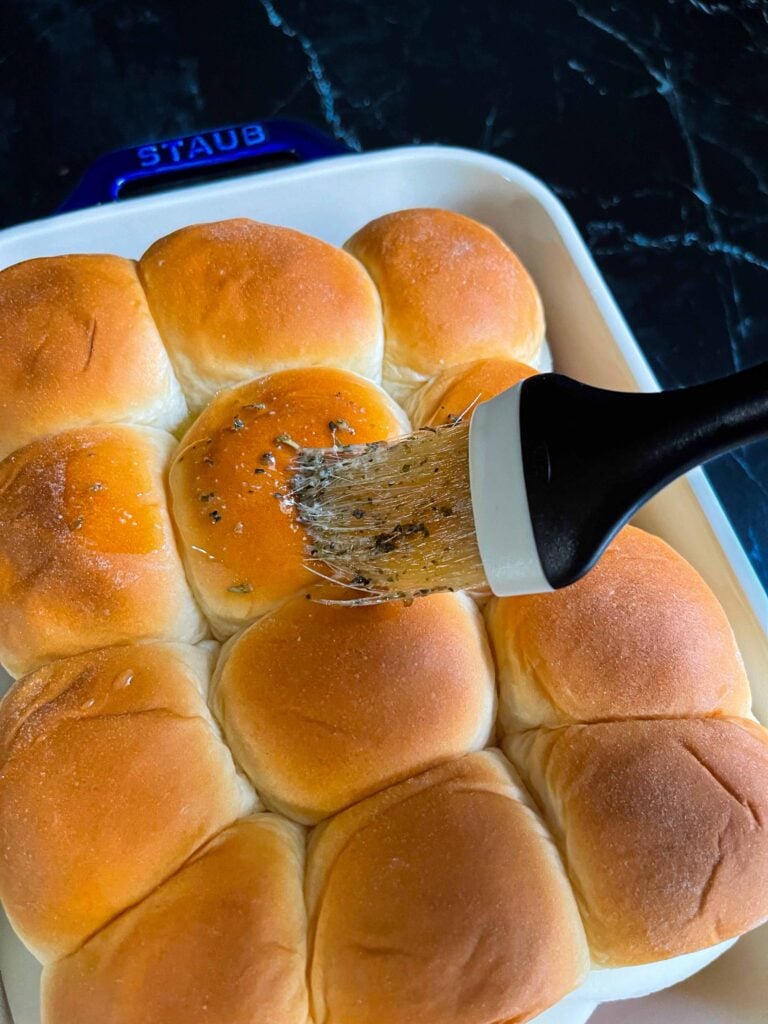 Brushing the tops of the chicken parmesan sliders with a buttery herb mixture.