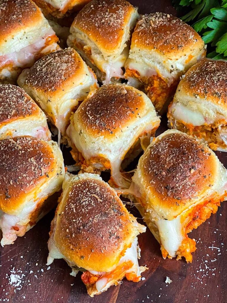 Chicken parmesan sliders on a wooden cutting board.