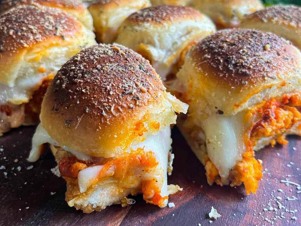 Chicken parmesan sliders on a wooden cutting board.