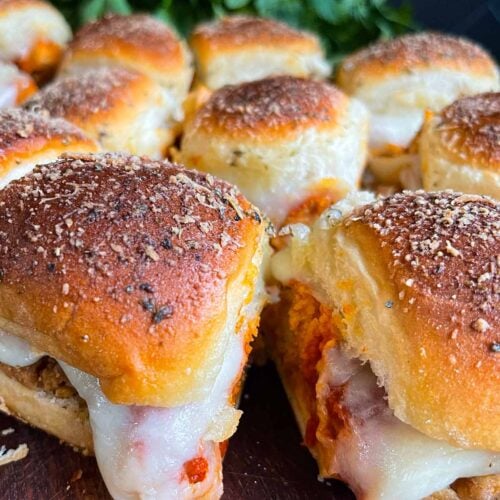 Chicken parmesan sliders on a wooden cutting board.