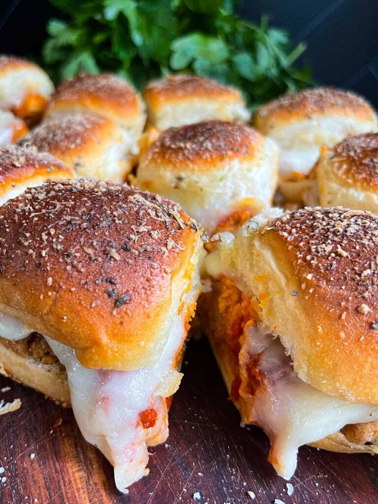 Chicken parmesan sliders on a wooden cutting board.